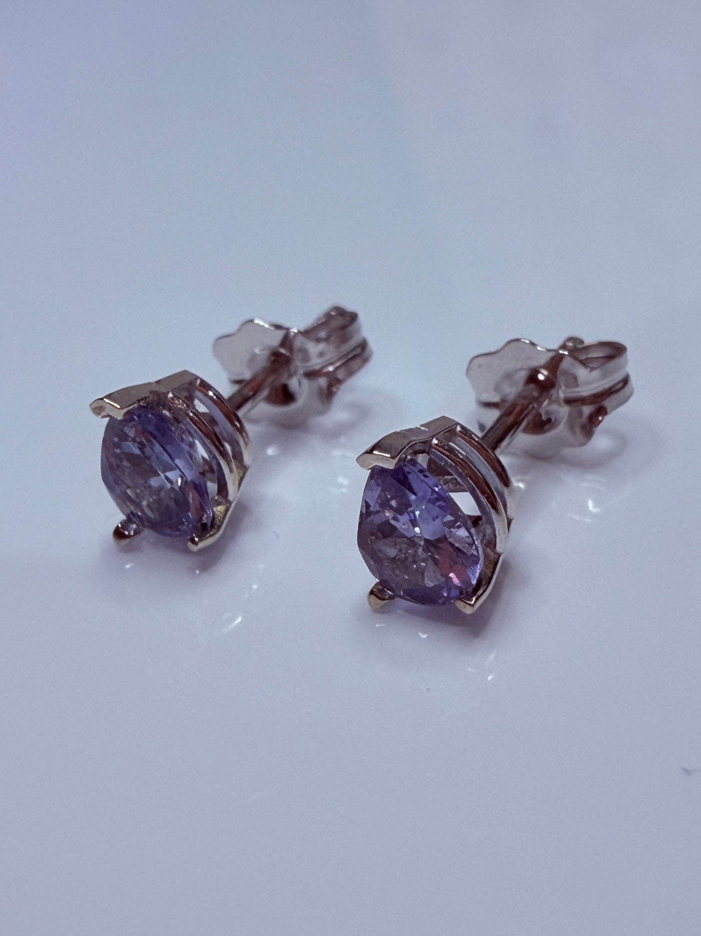 A pair of stud earrings with oval purple gemstones in a silver-toned setting, shown on a plain light background.