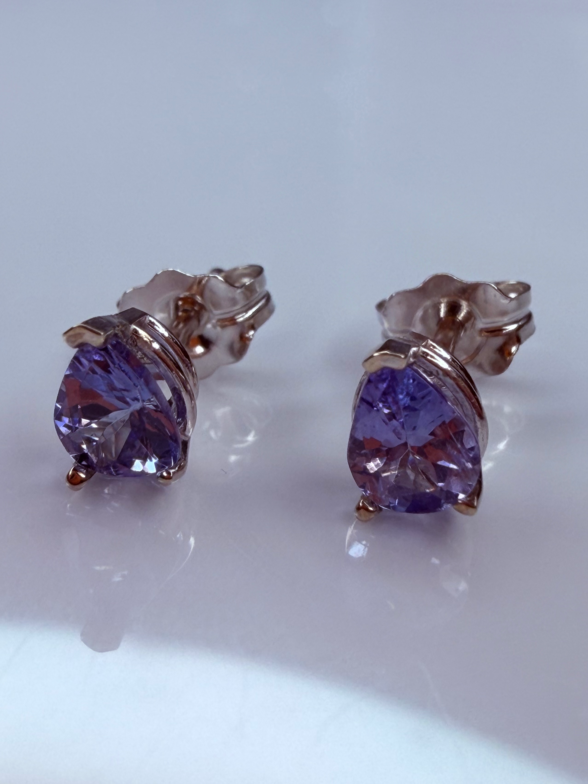 A pair of stud earrings featuring faceted tanzante gemstones in a white gold setting. 