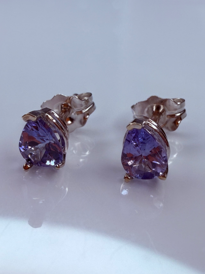 A pair of stud earrings featuring faceted tanzante gemstones in a white gold setting. 